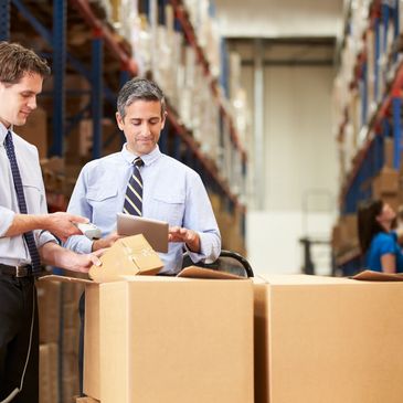 Two business professionals reviewing inventory on a tablet in a warehouse